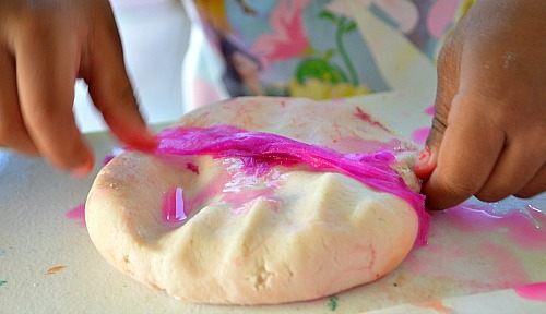 toddler sticking crepe paper on play dough